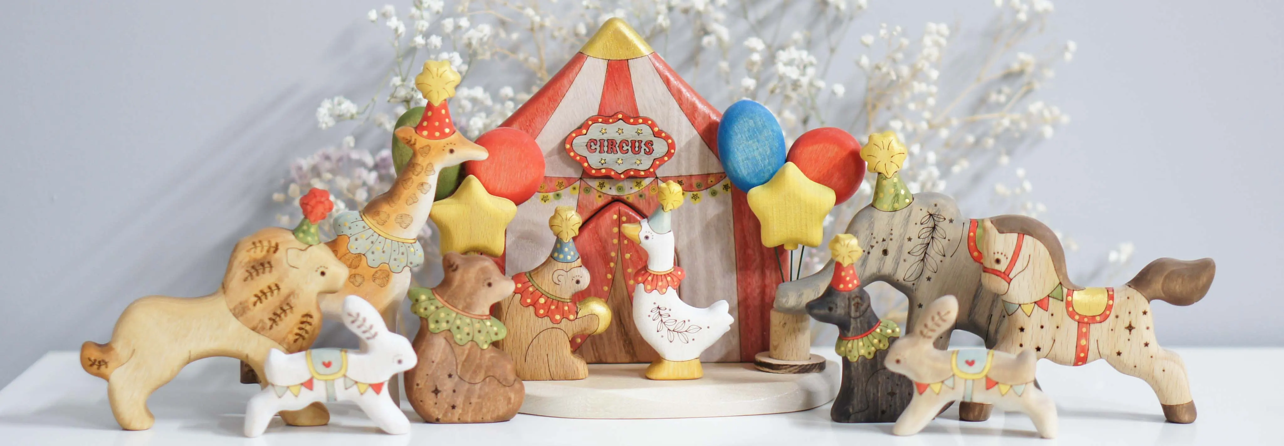 The Tiny Fox Hole circus: a striped tent surrounded by hand-painted wooden animals