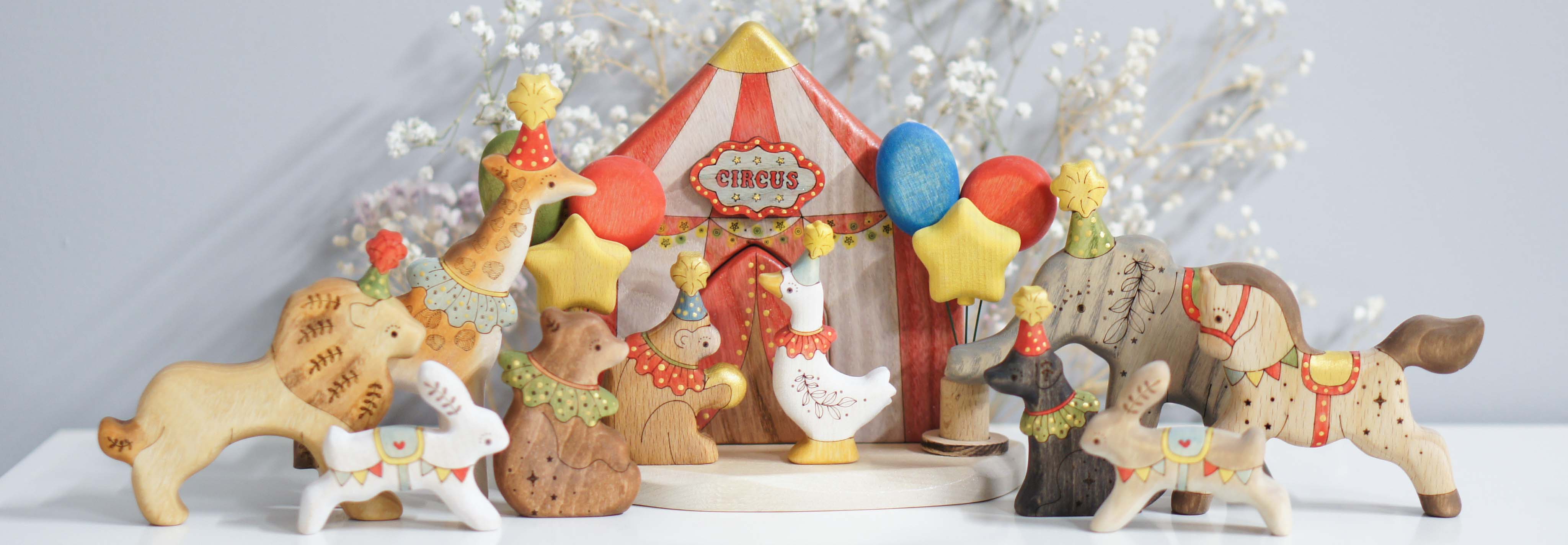 The Tiny Fox Hole circus: a striped tent surrounded by hand-painted wooden animals