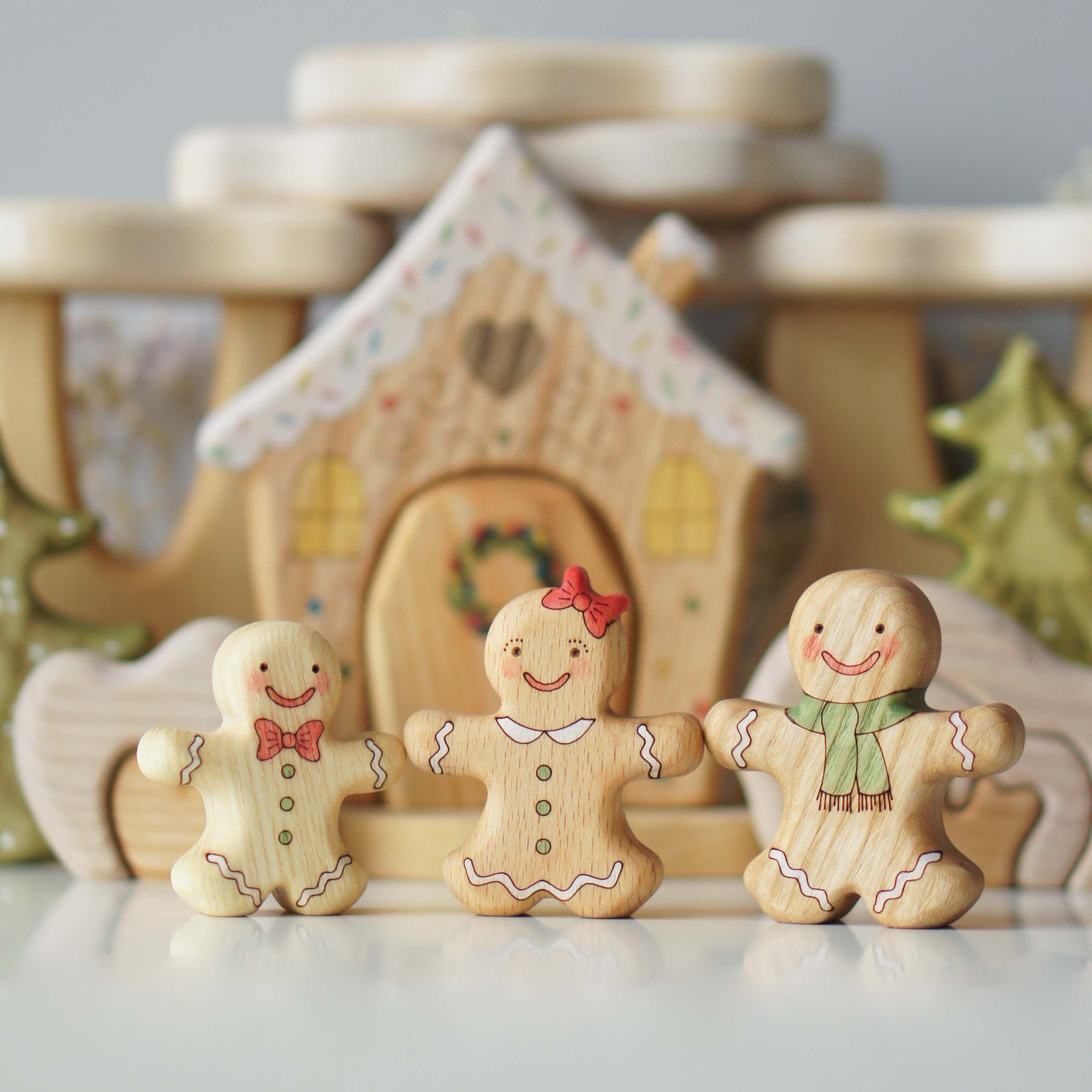 Three wooden gingerbread friends in front of their little house